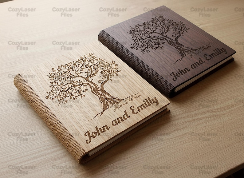 May include: Two wooden books with engraved tree designs. One book is light-colored, the other is dark. Both books have the names "John and Emilly" engraved on the cover. The books are on a light-colored wooden surface.
