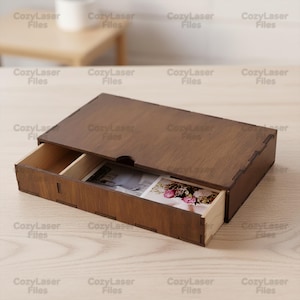May include: A wooden box with a sliding drawer, stained in a dark brown color. The drawer is partially open, revealing two photographs. The box is labeled with the text "CozyLaser Files".