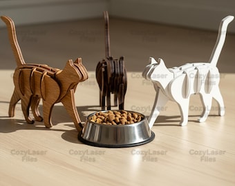Puede incluir: Figuras de gato de madera en marrón, marrón oscuro y blanco, con un cuenco para mascotas de acero inoxidable lleno de comida seca. Las figuras de gato están cortadas con láser. El cuenco tiene unos 15 cm de diámetro.