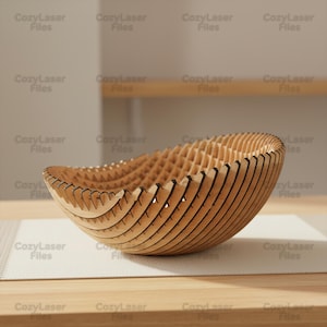 Puede incluir: Un cuenco decorativo de madera con un diseño único en capas. El cuenco está hecho de madera de color marrón claro y presenta una serie de listones curvos y paralelos, creando una superficie texturizada. El cuenco mide aproximadamente 30 cm de diámetro y 10 cm de alto.