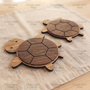 May include: Two turtle-shaped wooden coasters featuring a dark brown wood grain shell with a geometric hexagonal pattern and a lighter wood grain head and limbs. The text CozyLaser Files is repeated across the image surface.
