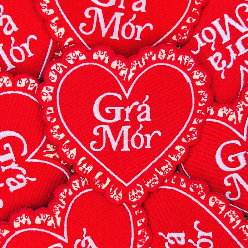 May include: A close-up of several red felt heart-shaped patches with white embroidered lettering that reads "Gr&aacute; M&oacute;r".