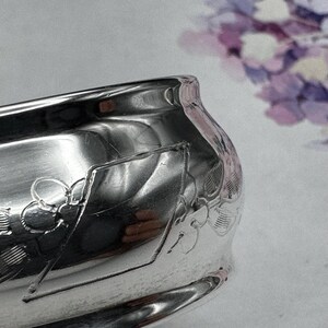 Op de afbeelding: Een zilveren kom met een sierlijk ontwerp. De kom is hoogglanzend gepolijst en reflecteert licht.