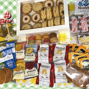 May include: A collection of British treats, including shortbread, cookies, tea bags, clotted cream, and pastries. Jars of honey and a variety of packaged snacks are arranged on a green and white checkered background.