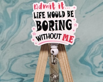 May include: White badge holder with a pink and black design that reads "Admit it... Life would be boring without me". The badge holder is on a small wooden easel.
