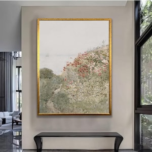 May include: A framed painting of a landscape with a path leading through a field of pink and red flowers. The background is a hazy blue sky and water.