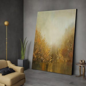 May include: A large abstract painting with a golden yellow and brown color scheme. The painting depicts a foggy landscape with tall grasses and a reflective body of water.