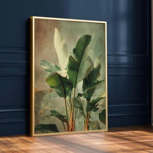 May include: A framed botanical print featuring lush green banana leaves with a light green and brown background. The leaves have a variety of shades of green and white. The frame is gold.