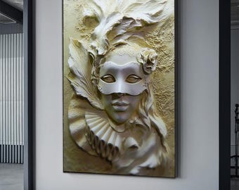 May include: A framed, three-dimensional artwork featuring a sculpted face wearing a white mask. The relief sculpture has a textured, off-white background with a feathered headdress and ruffled collar. A rose is placed near the head.