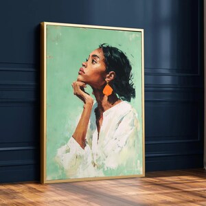 May include: A framed oil painting featuring a woman with dark hair and orange earrings. She wears a white shirt and gazes upwards, her hand resting on her chin. The background is a light green hue, and the frame is gold.
