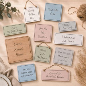 May include: A collection of rectangular and square wooden signs in pastel colors featuring black text. Phrases include Family Gather Here, Good Vibes Only, Enjoy the Little Things, You Are My Sunshine, Kitchen Open Daily, Home Sweet Home, Welcome to our Home, Please Water the Plants, DEAR VISITORS Please remove your shoes, ! NOTICE ! PLEASE KEEP GATE CLOSED, and Reserved For Grandma's Garden.