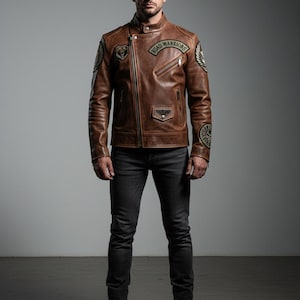 May include: A brown leather motorcycle jacket featuring an asymmetrical zipper, a snap-button collar, and multiple embroidered patches, including one on the chest that reads "ROAD WARRIORS" in black lettering, paired with dark gray denim jeans.