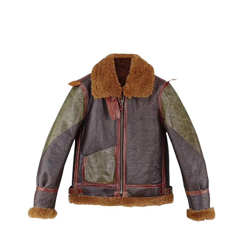 May include: A brown leather jacket with a shearling collar and lining. The jacket features olive green shoulder panels, a front zipper, and a pocket. The cuffs and hem are trimmed with shearling. The jacket has a vintage, aviator style.