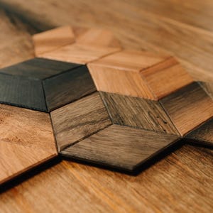 May include: A close-up of a wooden geometric pattern made of different shades of brown wood. The pattern is made up of hexagons and triangles.