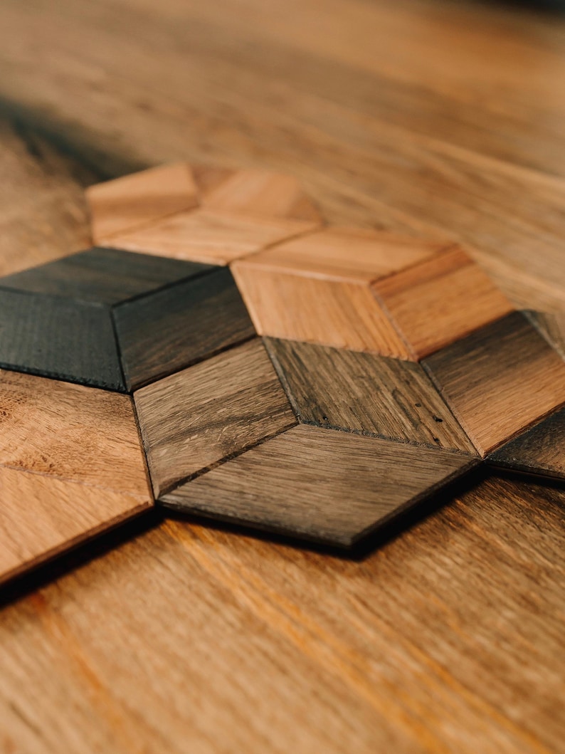 May include: A close-up of a wooden geometric pattern made of different shades of brown wood. The pattern is made up of hexagons and triangles.