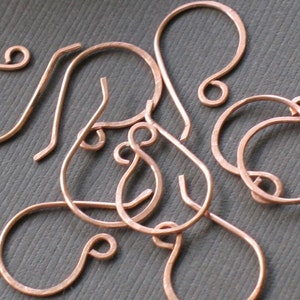 May include: A close-up of a group of copper earring hooks. The hooks are all in the shape of a teardrop with a small loop at the top.