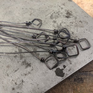 May include: A group of eight wire jewelry findings with a square loop at the end. The findings are made of copper wire and have a rustic, aged finish.