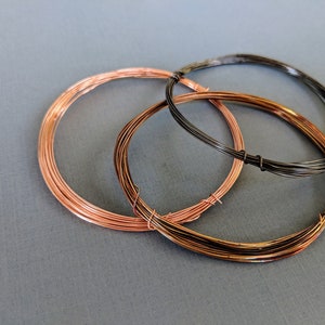 May include: Three spools of wire, one black, one copper, and one a combination of copper and black. The spools are arranged in a circle.