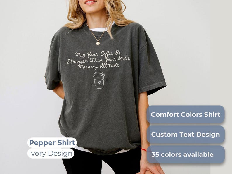 A person wearing a pepper-colored t-shirt with the text May Your Coffee Be Stronger Than Your Kid's Morning Attitude and a coffee cup graphic.