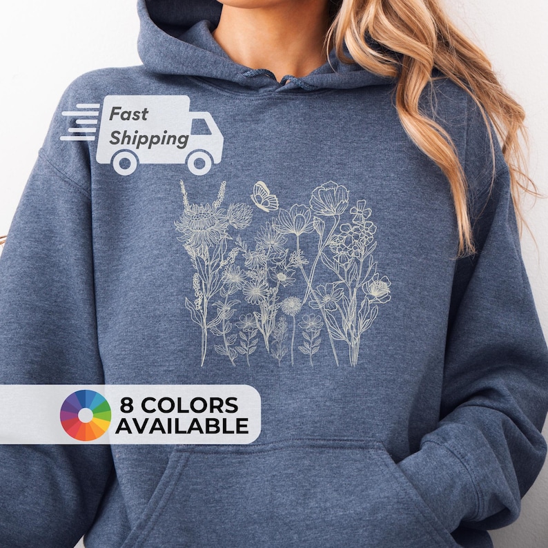 Pu&ograve; includere: Una felpa con cappuccio blu con un design floreale beige chiaro. La felpa ha una tasca frontale e un cappuccio. Il testo "8 COLORS AVAILABLE" &egrave; visualizzato in basso a sinistra nell'immagine.