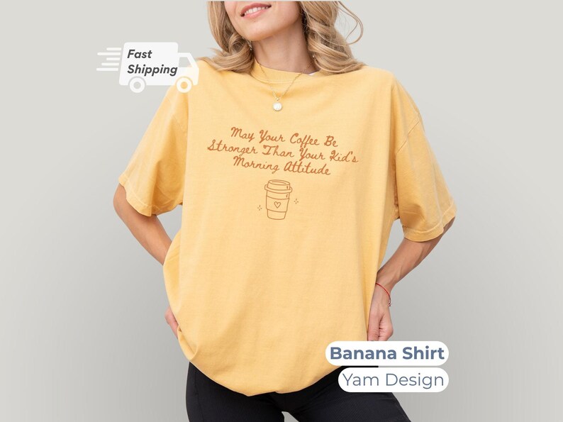 A model posing in a banana yellow t-shirt featuring yam-colored text and a coffee cup outline graphic.
