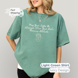A woman wearing a light green t-shirt with white text that reads May Your Coffee Be Stronger Than Your Kid's Morning Attitude alongside a coffee cup graphic.