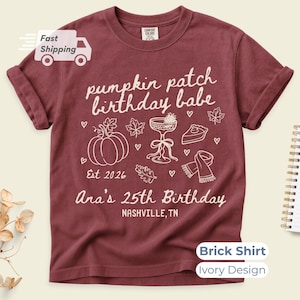 May include: A brick-coloured short-sleeve t-shirt featuring an ivory graphic design. The print includes the text "pumpkin patch birthday babe", "Est 2026", "Ana's 25th Birthday", and "NASHVILLE, TN", alongside illustrations of a pumpkin, a cocktail glass, a slice of pie, a scarf, and leaves.