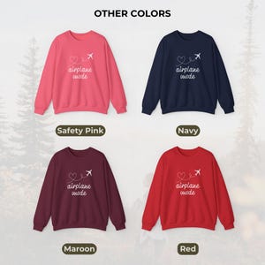 May include: A collection of four crewneck sweatshirts in various colors: safety pink, navy, maroon, and red. Each sweatshirt features the text "airplane mode" with a heart and airplane graphic in white.