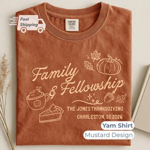 May include: A rust-colored crew neck t-shirt featuring a graphic print with the text Family & Fellowship, The Jones Thanksgiving, Charleston, SC 2026, alongside illustrations of a pumpkin, a mug, a slice of pie, an acorn, and leaves.