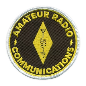 Peut inclure: Un écusson brodé jaune et noir avec le texte "Amateur Radio Communications" en cercle autour d'un losange jaune avec une antenne à l'intérieur.
