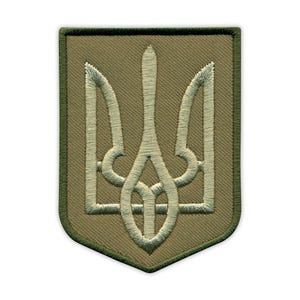 Puede incluir: Parche bordado con el escudo de armas ucraniano, un tridente, en color verde claro. El emblema está cosido en un tono más claro de verde sobre un fondo caqui, enmarcado por un borde verde oscuro. El parche es rectangular con esquinas redondeadas.