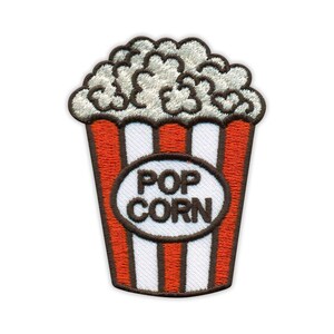Puede incluir: Parche de palomitas bordadas. El diseño presenta un recipiente a rayas rojas y blancas lleno de palomitas de maíz blancas y esponjosas. El parche tiene las palabras "POP CORN" en un óvalo blanco. El parche está delineado en marrón.