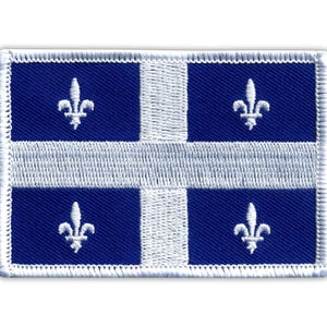 Op de afbeelding: Geborduurde patch met de vlag van Quebec. De rechthoekige patch heeft een wit kruis op een blauwe achtergrond, met een witte fleur-de-lis in elk van de vier blauwe kwadranten. De patch is omrand met witte stiksels.