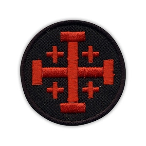 Peut inclure: Un patch circulaire noir avec une croix rouge brodée et quatre petites croix.