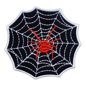May include: Embroidered patch featuring a red spider on a white web against a black background. The patch has a white stitched border and is in the shape of a spider web. Ideal for Halloween or spooky themed projects.