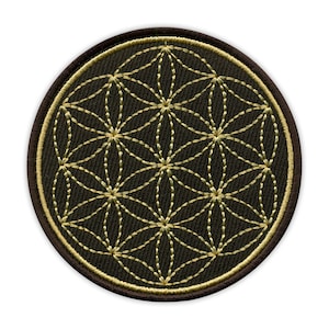 Könnte beinhalten: Runder Aufnäher mit einem goldfarbenen Flower-of-Life-Design auf dunkelbraunem Hintergrund. Der Aufnäher hat einen braunen Rand mit goldfarbenen Nähten. Das Flower of Life ist ein geometrisches Muster.