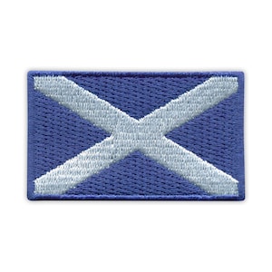 May include: A rectangular embroidered patch depicting the Scottish flag, also known as the Saltire. The patch has a blue background with a white diagonal cross. The edges are also blue. The patch is likely made of fabric.