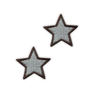 Op de afbeelding: Twee stervormige geborduurde patches met een lichtgrijs midden en een donkerbruine gestikte rand. De vijfpuntige sterontwerpen zijn identiek in vorm en kleur en vertonen een gestructureerd draadpatroon over het gehele oppervlak.