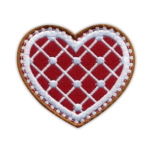 Può includere: Una toppa ricamata a forma di cuore con un centro rosso intenso e un motivo a griglia bianco sovrapposto. Il design include piccoli punti bianchi in ogni intersezione della griglia e il cuore è bordato da un spesso bordo marrone cucito.