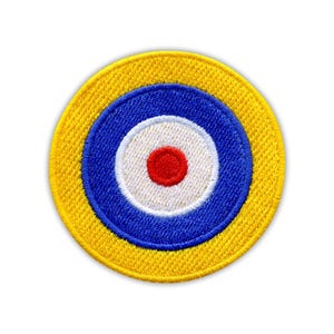 Può includere: Toppa rotonda ricamata con un design a bersaglio. La toppa ha un bordo esterno giallo, un anello blu, un anello bianco e un centro rosso. La toppa è rotonda e ha un aspetto strutturato.