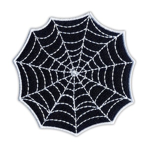 Könnte beinhalten: Ein schwarzer Spinnennetz-Aufnäher mit weißen Nähten. Der Aufnäher ist rund mit einem gewellten Rand. Das Spinnennetz-Design weist ein detailliertes Muster aus radialen Linien und konzentrischen Kreisen auf, ideal für Halloween-Projekte.