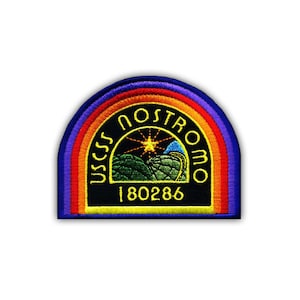 Peut inclure: Un écusson brodé noir et jaune avec une bordure arc-en-ciel. L'écusson présente le texte "USCSS Nostromo" et le numéro "180286".