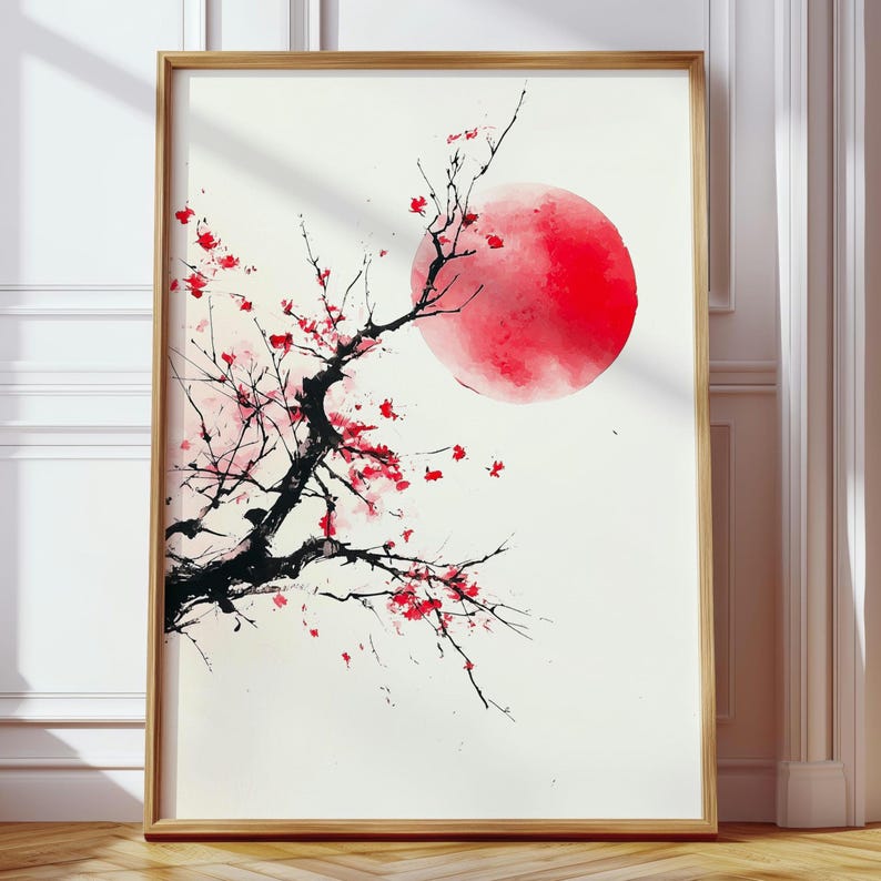 May include: A framed art print featuring a Japanese-inspired design. The artwork depicts a black tree branch with red blossoms against a large red sun on a white background. The frame is made of light-colored wood.