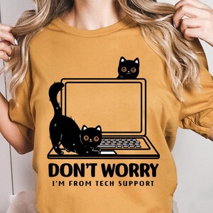 May include: A yellow t-shirt with a black cat sitting on a laptop. The text on the shirt reads "Don't worry I'm from tech support."