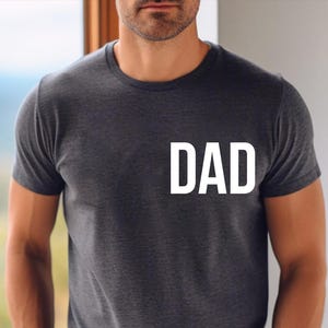 May include: A dark gray t-shirt with the word "DAD" printed in white on the front.