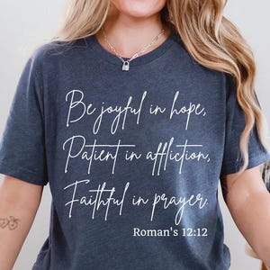 May include: A dark blue t-shirt with white text that reads "Be joyful in hope, Patient in affliction, Faithful in prayer. Roman's 12:12".