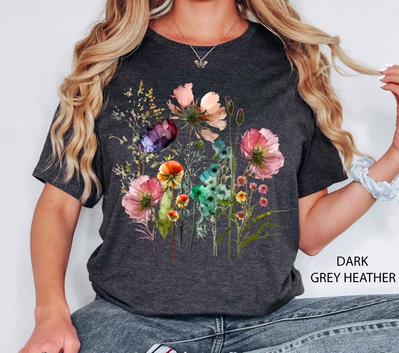 May include: Dark grey heather t-shirt featuring a watercolor floral design. The design includes pink, orange, purple, and blue flowers with green stems and leaves. The text "DARK GREY HEATHER" is printed on the bottom right.