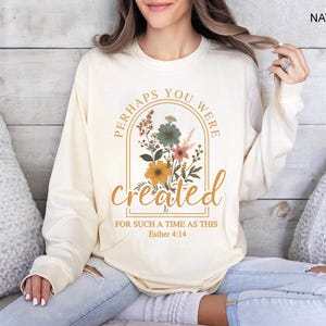 Może przedstawiać: Długi rękawowy t-shirt w kolorze kremowym z kwiatowym wzorem i tekstem "Perhaps you were created for such a time as this Esther 4:14".