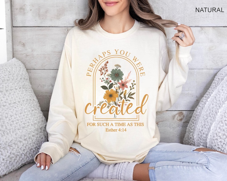 Może przedstawiać: Długi rękawowy t-shirt w kolorze kremowym z kwiatowym wzorem i tekstem "Perhaps you were created for such a time as this Esther 4:14".