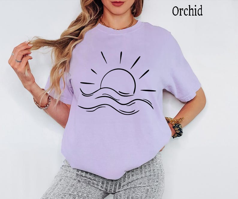 Pu&ograve; includere: Una t-shirt a maniche corte color orchidea con una grafica a linee nere che raffigura un sole che sorge sopra le onde dell'oceano. La parola Orchid &egrave; stampata nell'angolo in alto a destra. La maglietta ha un girocollo e una vestibilit&agrave; ampia.